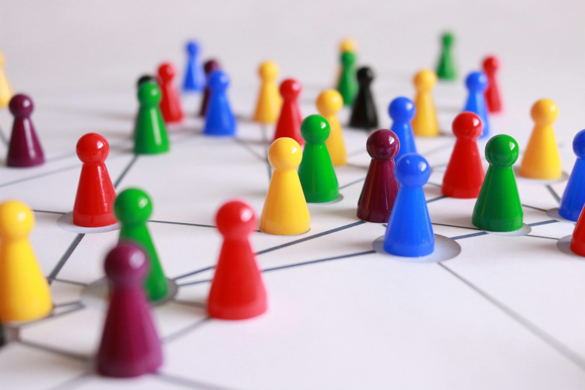 Eine strategische Anordnung bunter Spielfiguren auf einem Spielbrett, die Vernetzung und Teamarbeit symbolisiert.